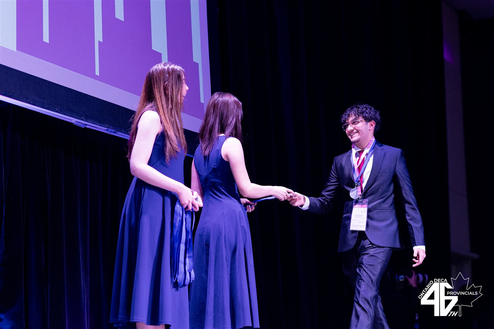 Turner Fenton DECA members exchanging awards on stage at Ontario DECA Provincials